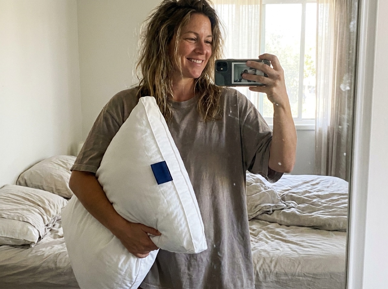 A well-rested customer holding her NOD pillow in the morning